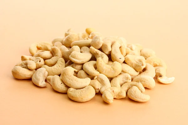 Välsmakande cashewnötter nötter, på beige bakgrund — Stockfoto