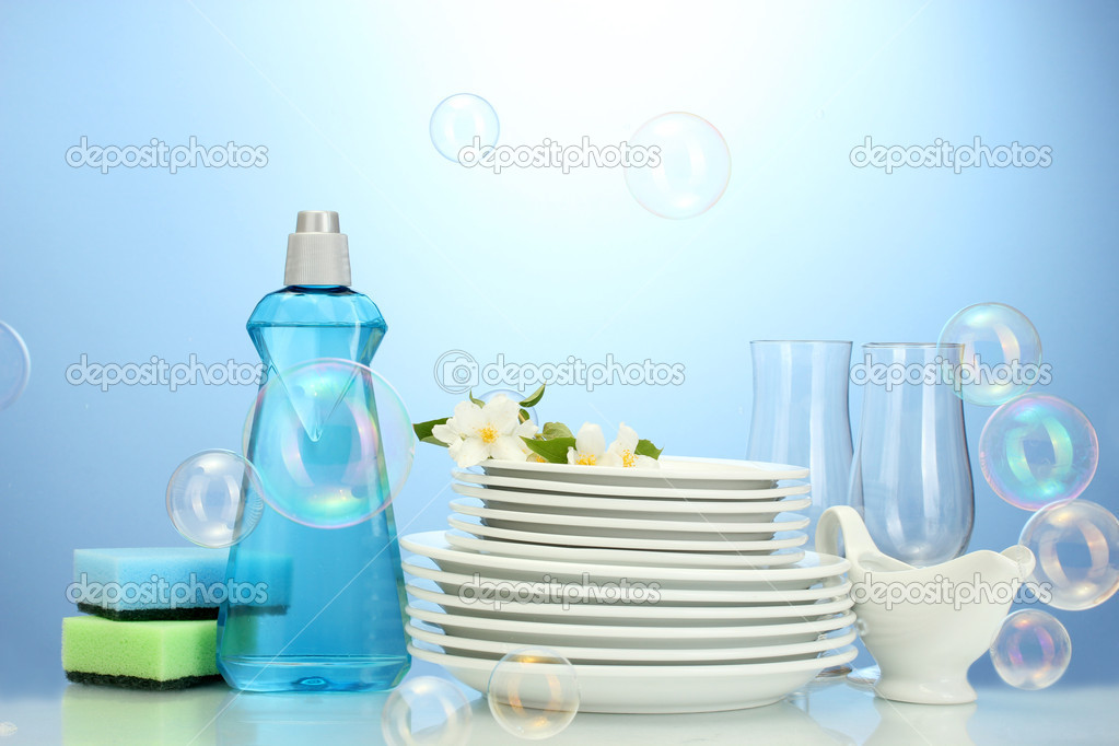 empty clean plates and glasses with dishwashing liquid, sponges and flowers