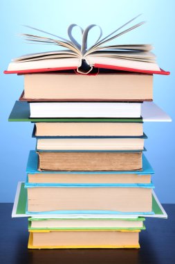 Stack of interesting books and magazines on wooden table on blue background clipart