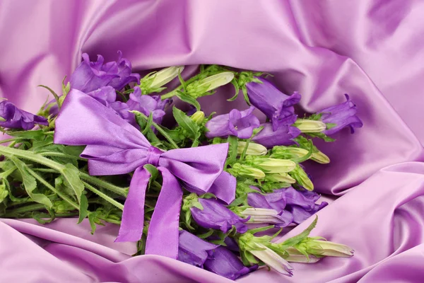 Mavi çan çiçekleri mor ipek kumaş üzerine — Stok fotoğraf