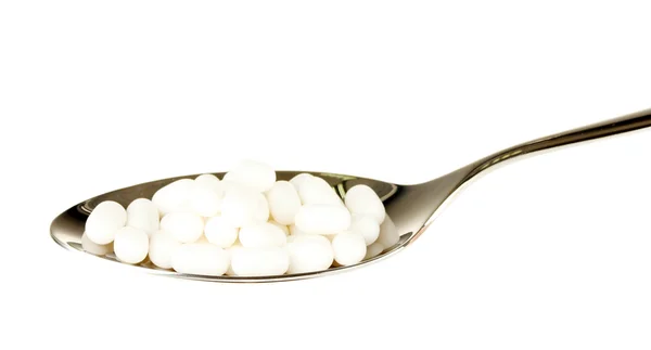 Pillole colorate su cucchiaio su sfondo bianco primo piano — Foto Stock