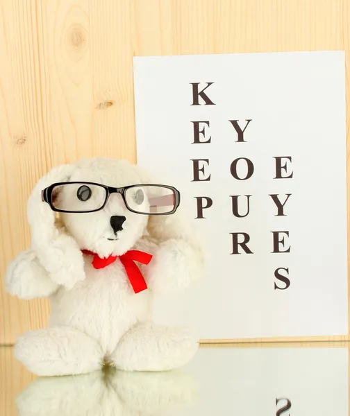 Eyesight test chart with glasses and with toy on wooden background close-up — Stock Photo, Image