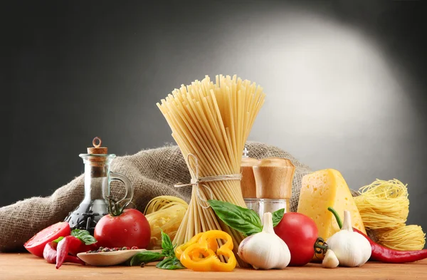 Espaguetis de pasta, verduras y especias, sobre mesa de madera, sobre fondo gris — Foto de Stock