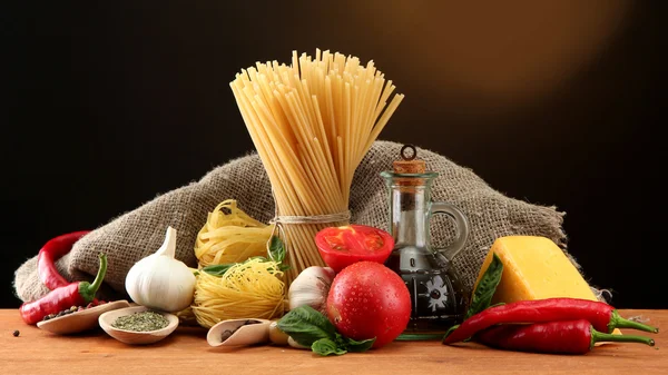 Nudelspaghetti, Gemüse und Gewürze, auf Holztisch, auf braunem Hintergrund — Stockfoto