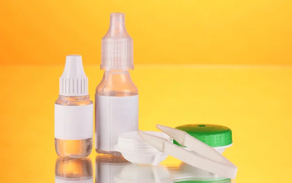 Eye drops and lenses on orange background — Stock Photo, Image