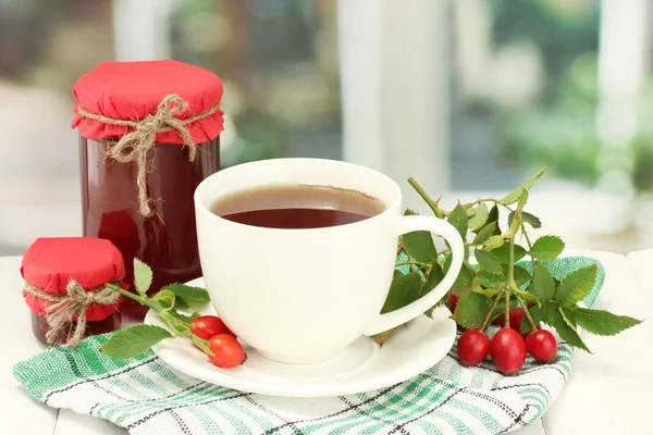 Tazza di tè con rose dell'anca, sul tavolo di legno — Foto Stock