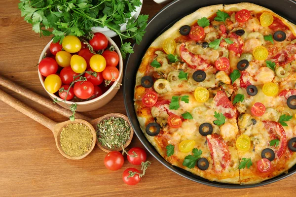 Farbenfrohe Komposition aus leckerer Pizza, Gemüse und Gewürzen auf Holzbalken — Stockfoto