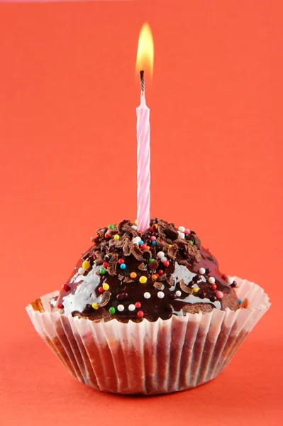 Tasty birthday cupcake with candle, on red background — Stock Photo, Image