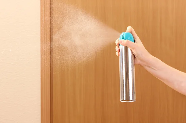 Sprayed air freshener in hand on room background — Stock Photo, Image