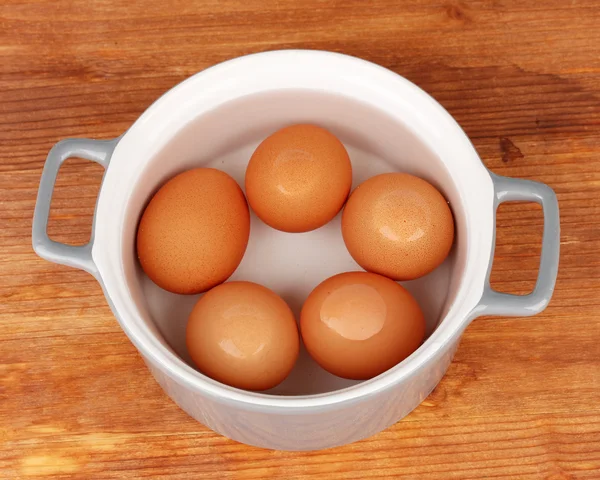 Boiled eggs in saucepan on wooden background — Stock Photo, Image