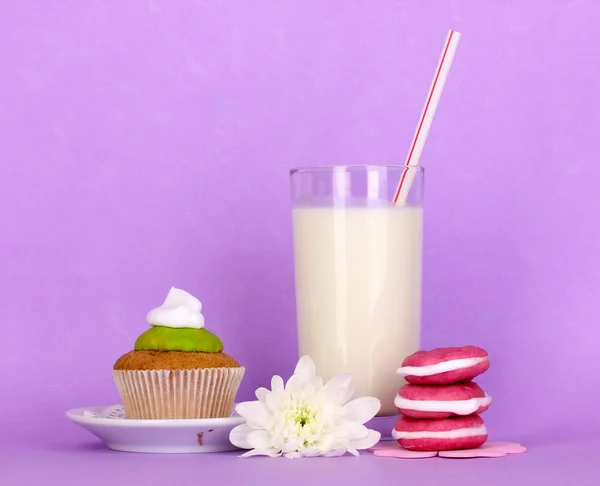 Glass of fresh new milk with cakes on purple background — Stock Photo, Image