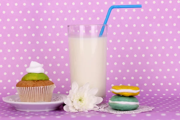 紫の水玉の背景に菓子と新鮮な新しいミルクのガラス — ストック写真