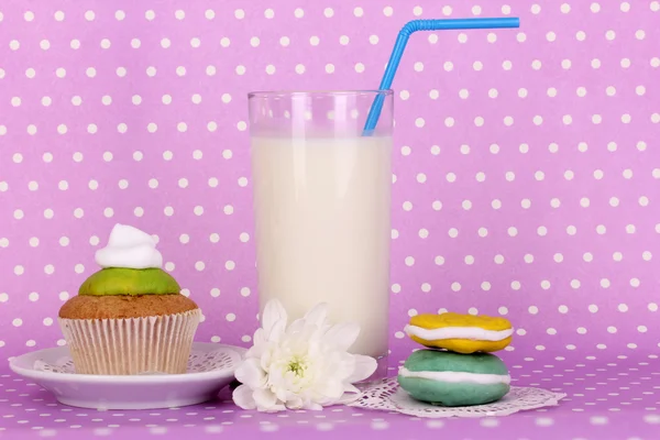 Verre de lait frais neuf avec des confiseries sur fond de pois pourpre — Photo