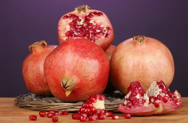 Reife Granatäpfel auf Weidenwippe auf violettem Hintergrund — Stockfoto