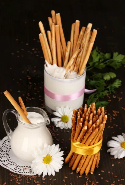 Tasty crispy sticks with pitcher and glass with sour cream on wooden table — Stock Photo, Image