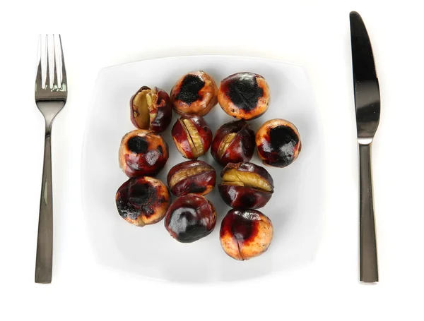 Roasted chestnuts in the white plate with fork and knife isolated on white Stock Image