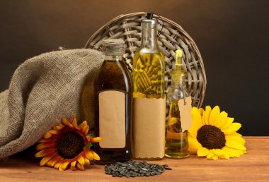 yağ şişeleri, ayçiçeği ve tohumlar kahverengi zemin üzerine ahşap masa üzerinde