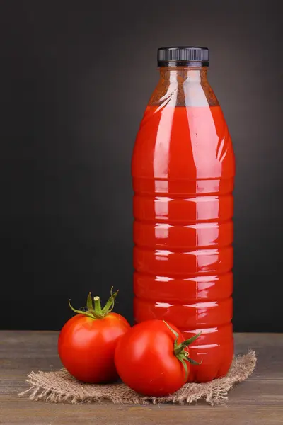 Jus de tomate en bouteille sur table en bois sur fond gris — Photo