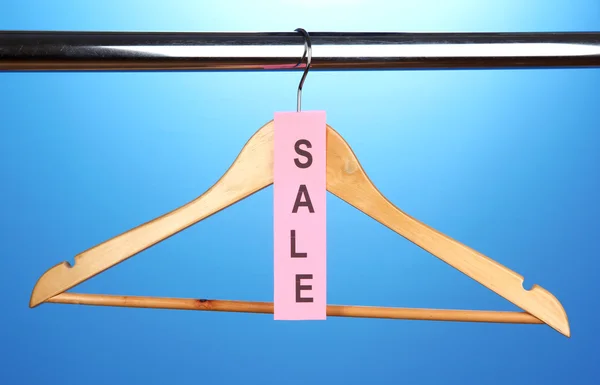 Wooden clothes hanger as sale symbol on blue background — Stock Photo, Image