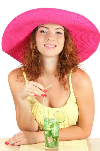 Смолящая красивая девушка, сидящая за столом в пляжной шляпе и коктейльном исо — стоковое фото