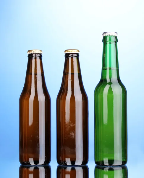 Бутылки пива на синем фоне — стоковое фото