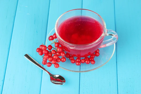 Glass cup with broth viburnum on blue wooden background close-up — Stock Photo, Image