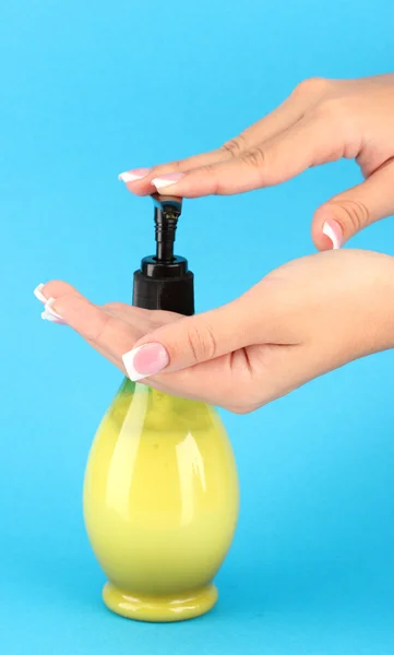 Woman squeezing lotion on her hand, on blue background close-up — Stock Photo, Image