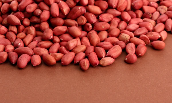 Leckere Erdnüsse, auf braunem Hintergrund — Stockfoto