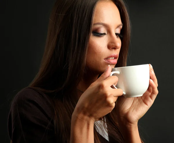 Hermosa joven con taza de café, sobre fondo marrón — Foto de Stock