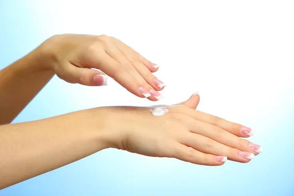 Beautiful woman hands with cream, on blue background — Stock Photo, Image