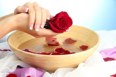 kadın eliyle su yaprakları, mavi zemin üzerine ahşap kase