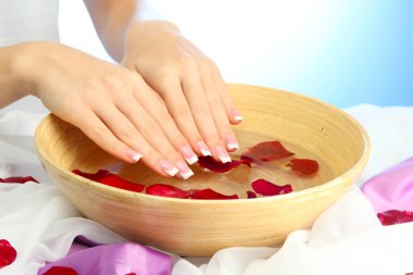 kadın eliyle su yaprakları, mavi zemin üzerine ahşap kase