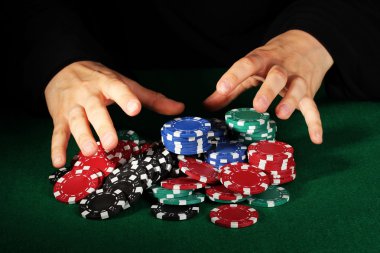 Poker fişleri ve yeşil masa üstündeki elleri