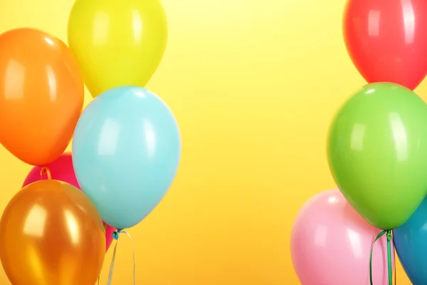 Красочные воздушные шары на желтом фоне крупным планом — стоковое фото