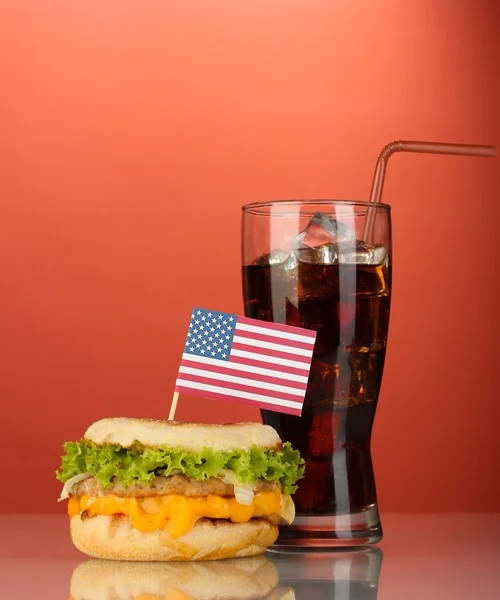 Sanduíche saboroso com bandeira americana e cola, em fundo vermelho — Fotografia de Stock