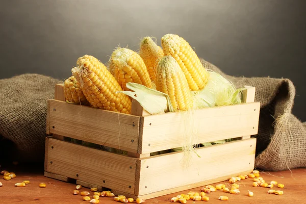 Färsk majs i rutan på träbord, på grå bakgrund — Stockfoto