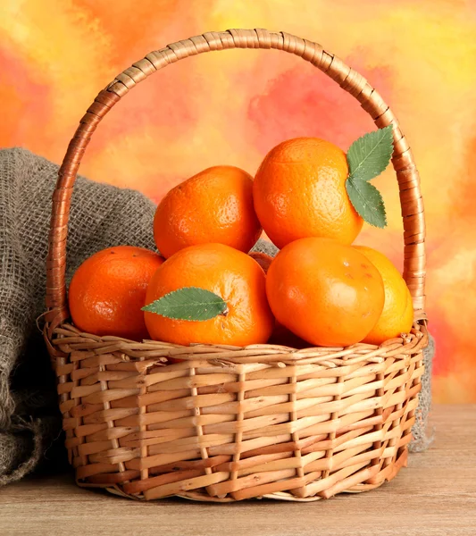 Tangerines με φύλλα σε ένα όμορφο καλάθι, στο ξύλινο τραπέζι — Φωτογραφία Αρχείου