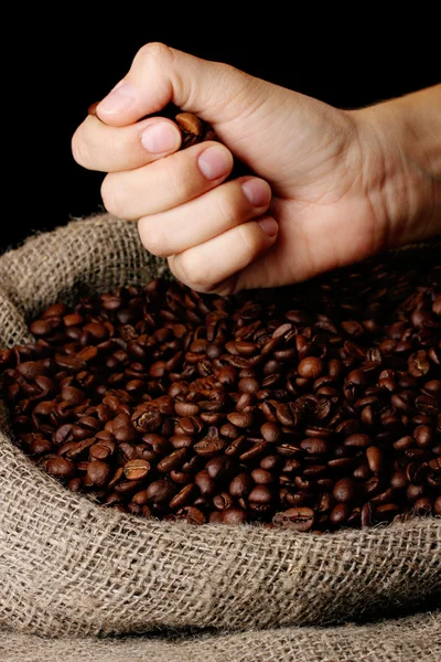 Coffee beans in hand on dark background — Stock Photo, Image