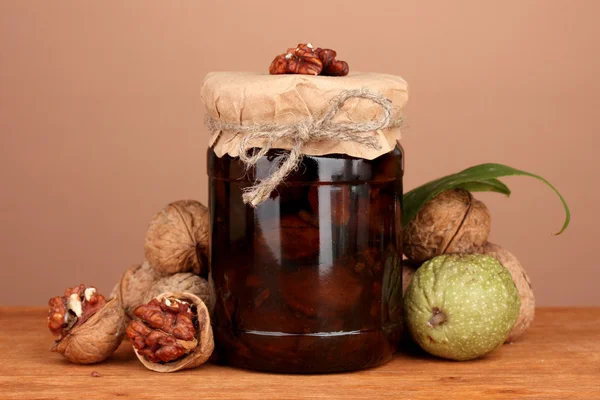 Jam-jar of walnuts on wooden table on brown background — Stock Photo, Image