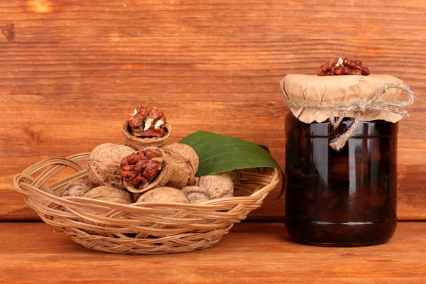 Marmellata-vaso di noci e cesto con noci su fondo marrone — Foto Stock