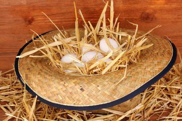 Экологически чистые яйца в шляпе на деревянном фоне — стоковое фото