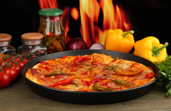 Tasty pepperoni pizza in pan with vegetables on flame background — Stock Photo, Image