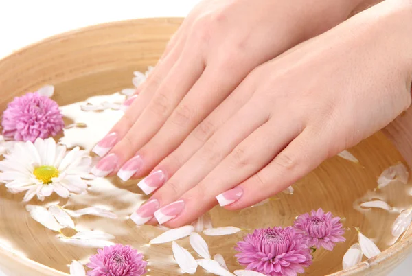 Woman hands with french manicure and flowers in bamboo bowl with water — Stock Photo, Image