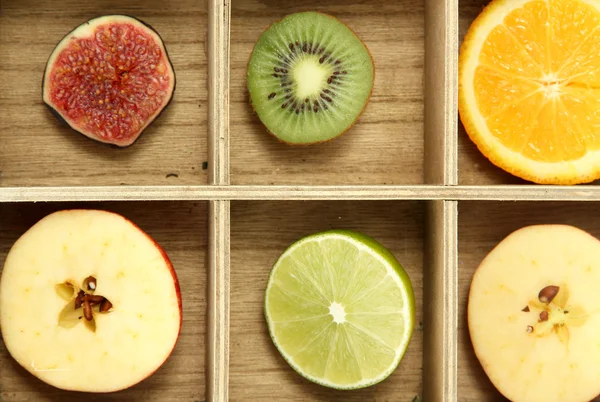 Sliced fruits in wooden box background — Stock Photo, Image