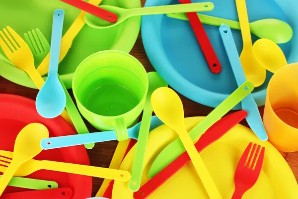 Světlé plastové jednorázové nádobí na detail dřevěné pozadí — Stock fotografie