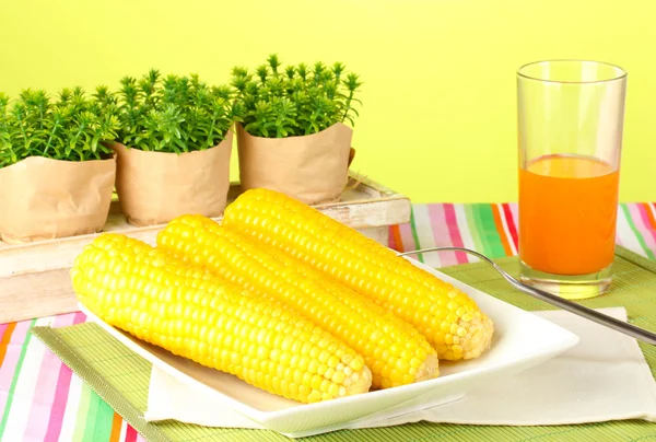 Boiled corn and juice on a green background — Stock Photo, Image