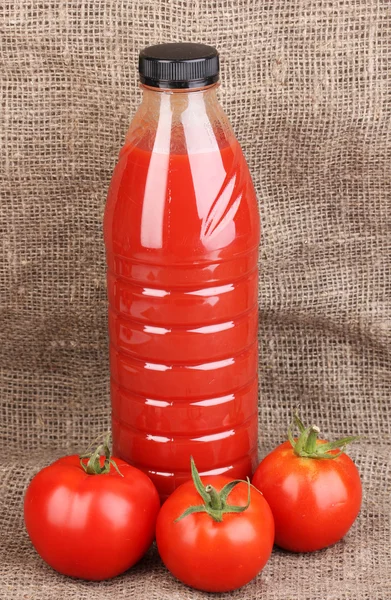 Jugo de tomate en botella sobre fondo de saco —  Fotos de Stock