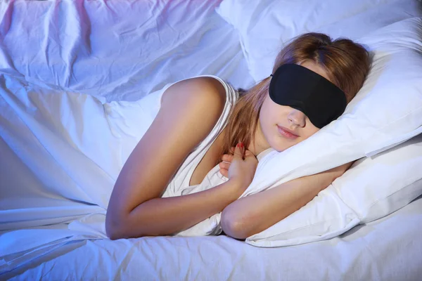 Giovane bella donna con maschera occhi dormire sul letto in camera da letto — Foto Stock