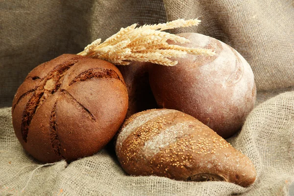 Smakelijke rogge brood met oren, op jute achtergrond — Stockfoto
