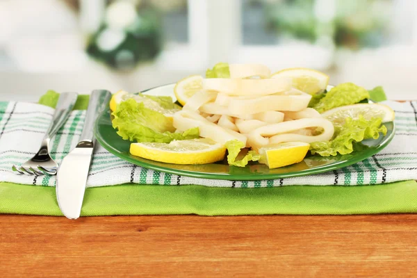 Gekookt inktvis ringen op sla met citroen op de plaat close-up — Stockfoto